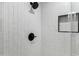 Bright shower with stylish black fixtures, a built-in shelf, and sleek, white tiling with a glass enclosure at 4955 E Indian School Rd # 5, Phoenix, AZ 85018