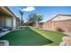 Artificial grass backyard featuring a lush lawn, privacy wall, and a mature palm tree at 6774 S Pinehurst Dr, Gilbert, AZ 85298