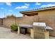 Outdoor kitchen with a stainless steel gas grill and bar seating at 7769 S Reseda St, Gilbert, AZ 85298