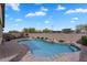Sparkling pool with a rock waterfall feature, lush landscaping, and patio seating at 7769 S Reseda St, Gilbert, AZ 85298