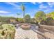 Backyard featuring a central fire pit, stone landscaping, and mature trees at 9231 E Carmel Ave, Mesa, AZ 85208