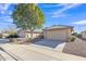 Inviting single-story home with desert landscaping, a mature shade tree, and a neutral-toned facade with a tiled roof at 9231 E Carmel Ave, Mesa, AZ 85208