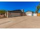 View of the home's exterior featuring an extended driveway and detached garages with painted brick at 1002 W Fairway Dr, Mesa, AZ 85201