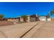 View of the home's exterior featuring an extended driveway and detached garages with painted brick at 1002 W Fairway Dr, Mesa, AZ 85201