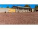 Single story home with neutral painted brick, desert rock yard, and wood accent fencing at 1002 W Fairway Dr, Mesa, AZ 85201