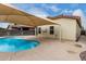 A backyard pool with a large sunshade, concrete patio, and a view of the tan stucco home at 1414 W Alder Rd, Queen Creek, AZ 85140