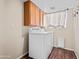 Bright laundry room features a white washer and dryer set, wood cabinets, and dark wood-look flooring at 14317 N 78Th Dr, Peoria, AZ 85381