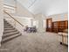 Spacious living room with a staircase, table, and bookshelf. It features carpeted floors and high ceilings at 14317 N 78Th Dr, Peoria, AZ 85381