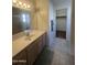 A clean bathroom with a vanity, a large mirror, and a walk-in closet offering storage at 14527 W Marcus Dr, Surprise, AZ 85374