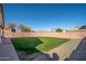 Wide backyard is fully fenced and landscaped with rocks and grass at 14717 N 130Th Ln, El Mirage, AZ 85335