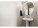 Clean and simple powder room with a pedestal sink, round mirror, and neutral decor at 15239 W Alexandria Way, Surprise, AZ 85379