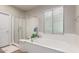 Bathroom with a soaking tub, glass-enclosed shower, and window with blinds allowing for natural light at 15239 W Alexandria Way, Surprise, AZ 85379