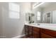 Bathroom featuring a double vanity sink and wood cabinetry, a decorative mirror, and tile flooring at 15239 W Alexandria Way, Surprise, AZ 85379