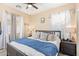 Well-lit bedroom with ceiling fan, white curtains, and bed with gray frame and blue blanket at 15239 W Alexandria Way, Surprise, AZ 85379