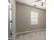 Bright bedroom with neutral carpeting, baseboards, window with blinds, ceiling fan and paint, with a white door and trim at 15239 W Alexandria Way, Surprise, AZ 85379