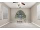 Neutral carpeted bedroom with a large arched window, ceiling fan, and a sitting bench at 15239 W Alexandria Way, Surprise, AZ 85379