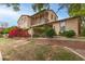 Charming two-story home with balcony, red flowers, lush greenery, and a classic brick retaining wall at 15239 W Alexandria Way, Surprise, AZ 85379