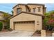 Tan two-story home featuring an attached two-car garage, neutral colors, and desert landscaping at 15239 W Alexandria Way, Surprise, AZ 85379