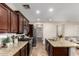 Spacious kitchen featuring dark wood cabinets, granite countertops, stainless steel appliances, and center island with sink at 15239 W Alexandria Way, Surprise, AZ 85379