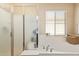 The bathroom has a soaking tub, glass-enclosed shower, and large basket for storing towels at 15239 W Alexandria Way, Surprise, AZ 85379