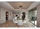 Dining room featuring a glass table with white chairs, stylish light fixture, and a built-in bar at 15802 N 71St St # 501, Scottsdale, AZ 85254