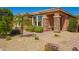 Inviting front exterior with desert landscaping, stone pillars, covered porch, and a small palm tree at 18118 W Redwood Ln, Goodyear, AZ 85338