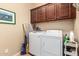 Laundry room includes modern washer and dryer, upper cabinets and neutral walls at 18118 W Redwood Ln, Goodyear, AZ 85338