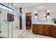 Bright main bathroom showcasing a glass shower, double vanity with wood cabinets, and access to the walk-in closet at 22181 N 78Th St, Scottsdale, AZ 85255