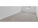 A minimalist bedroom with neutral carpet, white walls, and a window at 23435 W Albeniz Pl, Buckeye, AZ 85326