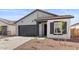 Charming single-Gathering home showcasing a gray facade, black trim, and a well-manicured front yard with a concrete driveway at 23435 W Albeniz Pl, Buckeye, AZ 85326
