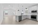 Open-concept kitchen featuring white cabinetry, a large island with seating, stainless steel appliances, and wood-look tile flooring at 23435 W Albeniz Pl, Buckeye, AZ 85326