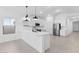 Modern kitchen with white cabinets, stainless steel appliances, a spacious island, and open views, enhanced by overhead lighting at 23435 W Albeniz Pl, Buckeye, AZ 85326