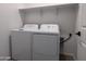 Functional laundry room with a new white washer and dryer and shelving that offers ample storage space at 24080 W Bowker St, Buckeye, AZ 85326