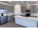 Spacious kitchen features gray cabinets, stainless steel appliances, an island and wood-look tile flooring at 24088 W Bowker St, Buckeye, AZ 85326
