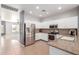 Well-lit kitchen featuring stainless steel appliances, white cabinets, granite countertops, and a large refrigerator at 24824 W Pueblo Ave, Buckeye, AZ 85326