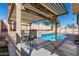 Inviting backyard featuring a sparkling pool with a waterfall feature and a comfortable seating area under a shaded pergola at 24824 W Pueblo Ave, Buckeye, AZ 85326