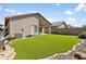 Wide view of the home's backyard with artificial grass, covered patio, and desert landscaping at 3407 W Steinbeck Dr, Anthem, AZ 85086