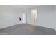 Bright empty bedroom showcases neutral carpet flooring and an open doorway to another room at 40005 W Rio Lobo Dr, Maricopa, AZ 85138