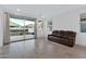 Bright living room features tile flooring, a leather couch, and sliding glass doors to backyard at 40005 W Rio Lobo Dr, Maricopa, AZ 85138