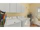 Functional laundry room with full-size washer and dryer, upper cabinets, and ample space for laundry tasks at 5206 N 16Th Dr, Phoenix, AZ 85015