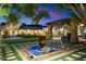 A tranquil backyard showcasing a fountain, manicured lawn, and covered patio, ideal for relaxation and outdoor gatherings at 6402 E Chaparral Rd, Paradise Valley, AZ 85253