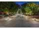 Long driveway leading to a home with mature trees, decorative bushes, and ambient lighting at 6402 E Chaparral Rd, Paradise Valley, AZ 85253