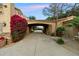 An elegant driveway leads to the home, framed by a flowering bush and verdant landscaping, enhancing curb appeal at 6402 E Chaparral Rd, Paradise Valley, AZ 85253