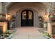 Elegant arched front door framed by flowers, planters and stone accents; brick walkway at 6402 E Chaparral Rd, Paradise Valley, AZ 85253