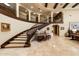 Sweeping staircase in a grand foyer with iron railings, travertine flooring, and decorative table at 6402 E Chaparral Rd, Paradise Valley, AZ 85253