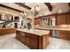 Expansive kitchen features an oversized island, wood cabinetry, tile backsplash, and stainless steel appliances at 6402 E Chaparral Rd, Paradise Valley, AZ 85253