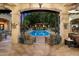 A picturesque pool area framed by arched openings, inviting seating, and lush greenery, offering a serene outdoor escape at 6402 E Chaparral Rd, Paradise Valley, AZ 85253
