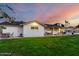 This backyard features green grass, a covered patio, and a white home at sunset at 6718 N 19Th Pl, Phoenix, AZ 85016