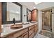 Bathroom with dual wood bowl sinks, vanity, and a glass shower with travertine surround at 902 W Moon Valley Dr, Phoenix, AZ 85023
