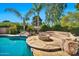 Beautiful backyard oasis with a pool, rock features, lush landscaping, and stone-paved firepit lounge at 902 W Moon Valley Dr, Phoenix, AZ 85023